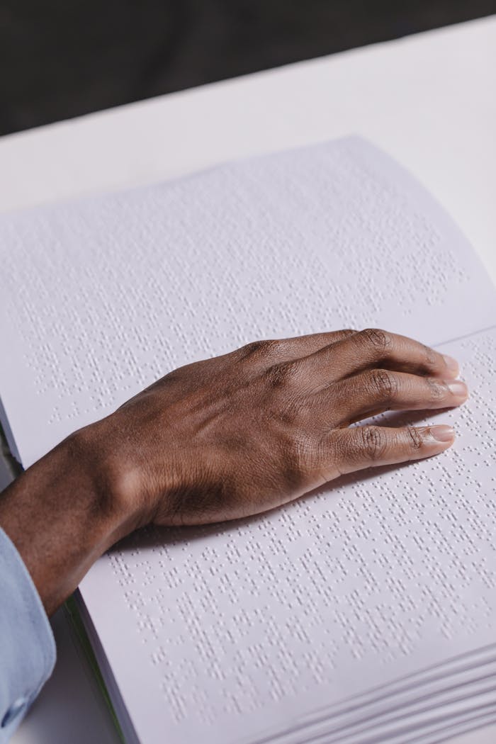 A close-up shot of a hand reading Braille text, highlighting visual impairment and tactile learning.